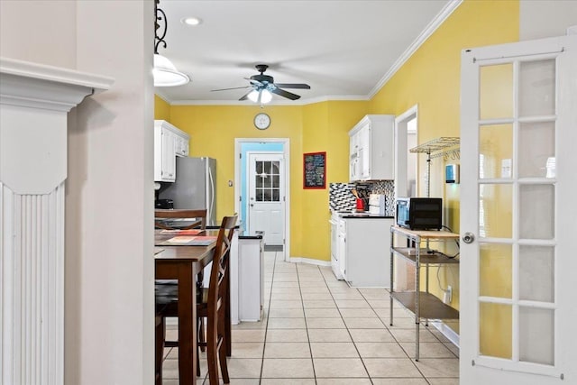 kitchen featuring tasteful backsplash, ceiling fan, white appliances, white cabinetry, and ornamental molding