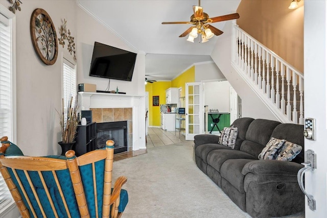 living room with ceiling fan, a tile fireplace, light carpet, and vaulted ceiling