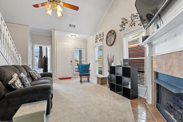 living room with carpet, ceiling fan, vaulted ceiling, a healthy amount of sunlight, and a tiled fireplace