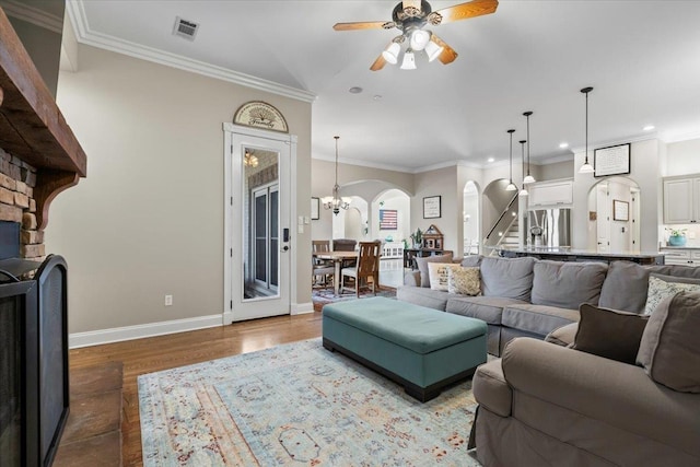 living room featuring ceiling fan with notable chandelier, hardwood / wood-style floors, and ornamental molding