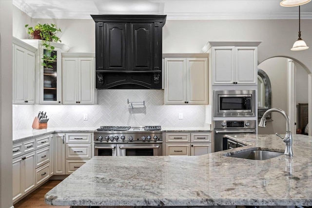 kitchen with light stone countertops, pendant lighting, appliances with stainless steel finishes, sink, and backsplash