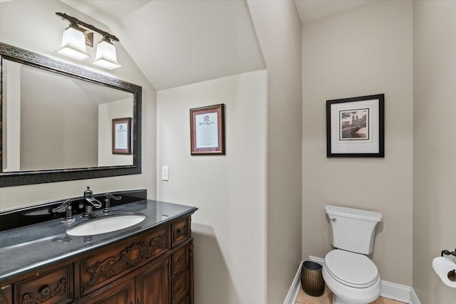 bathroom with toilet, vanity, and lofted ceiling