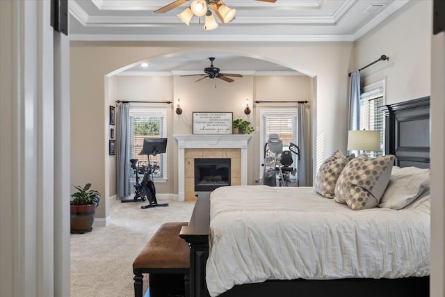 carpeted bedroom featuring ceiling fan, a tile fireplace, and ornamental molding