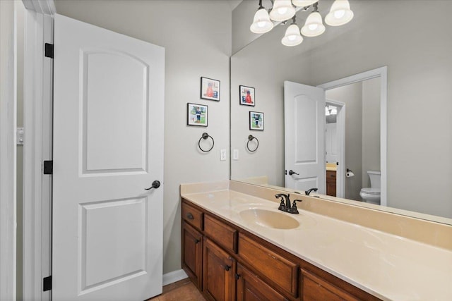 bathroom with toilet, vanity, and tile patterned flooring