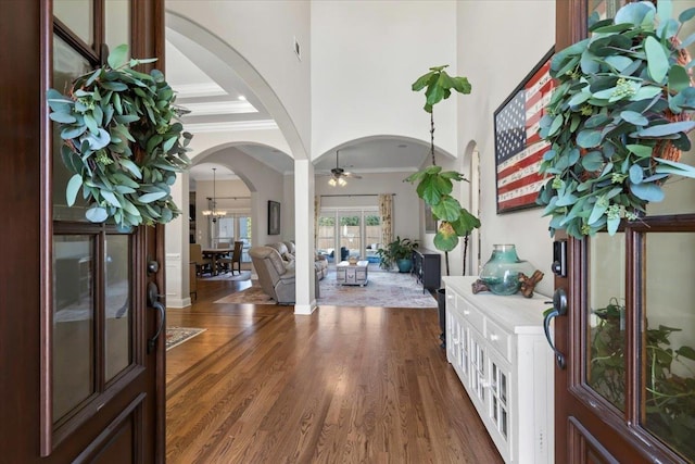 foyer with ceiling fan, a high ceiling, dark hardwood / wood-style floors, and crown molding