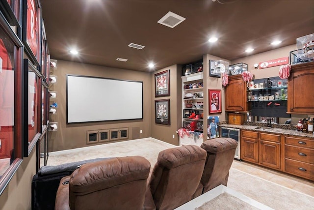 carpeted cinema room featuring beverage cooler and wet bar