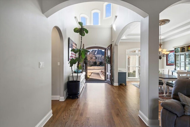 foyer featuring an inviting chandelier, ornamental molding, and dark hardwood / wood-style flooring