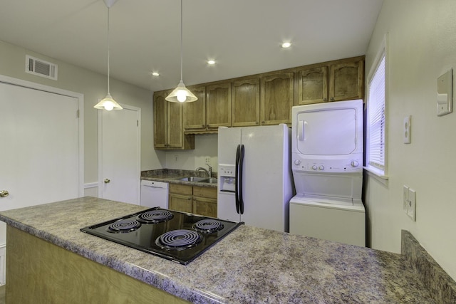 kitchen featuring stacked washer / dryer, sink, white appliances, and decorative light fixtures