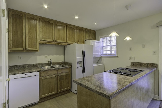 kitchen featuring stacked washer and clothes dryer, light hardwood / wood-style floors, decorative light fixtures, white appliances, and sink