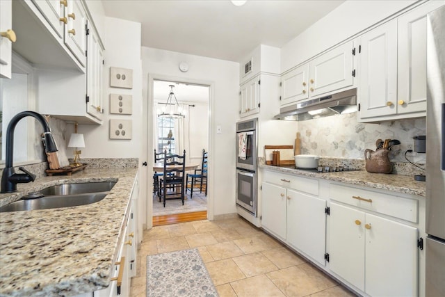 kitchen with tasteful backsplash, sink, white cabinetry, light stone countertops, and black electric cooktop