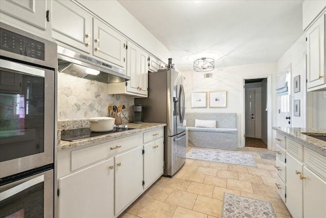 kitchen with light stone countertops, white cabinets, backsplash, and appliances with stainless steel finishes