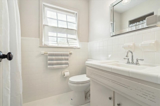 bathroom with toilet, tile walls, and vanity