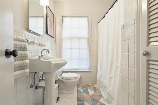 bathroom featuring toilet, a healthy amount of sunlight, tile walls, and tile patterned flooring