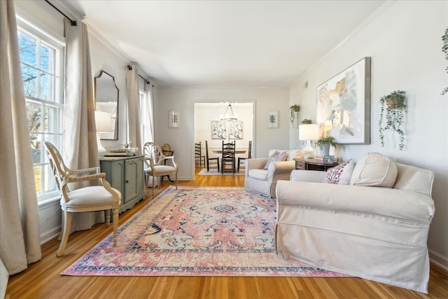 living room with light hardwood / wood-style flooring, crown molding, and a chandelier