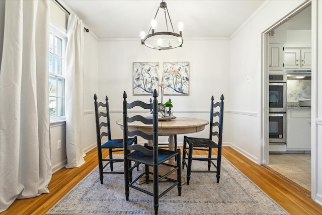 dining room with plenty of natural light, an inviting chandelier, ornamental molding, and light hardwood / wood-style flooring