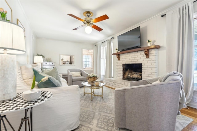 living room featuring ceiling fan, a brick fireplace, ornamental molding, and hardwood / wood-style floors