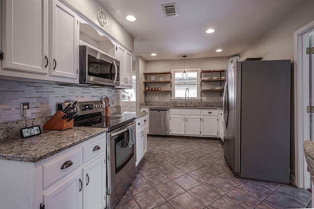 kitchen featuring stainless steel appliances, pendant lighting, white cabinets, and sink