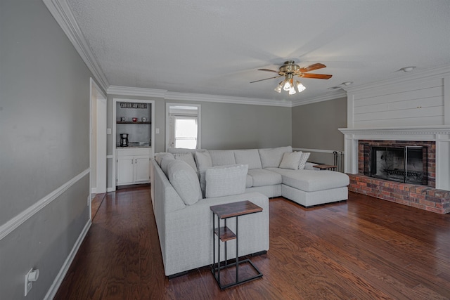 living room with ceiling fan, dark hardwood / wood-style floors, ornamental molding, and a fireplace