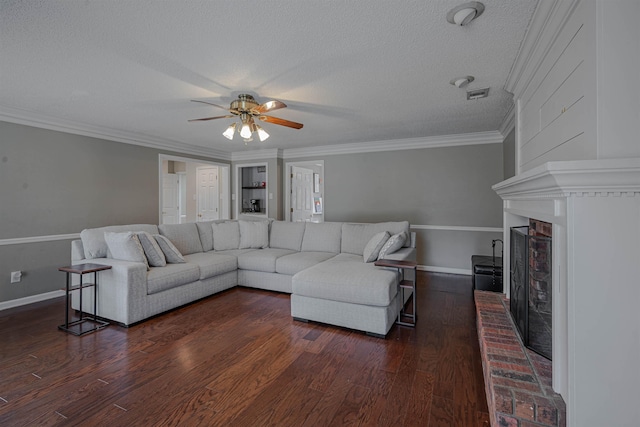 living room featuring ceiling fan, dark hardwood / wood-style floors, a fireplace, a textured ceiling, and ornamental molding