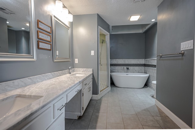 bathroom featuring a tub to relax in, vanity, tile patterned flooring, and a textured ceiling