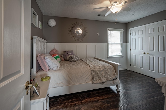 bedroom with ceiling fan, a closet, dark hardwood / wood-style floors, and a textured ceiling