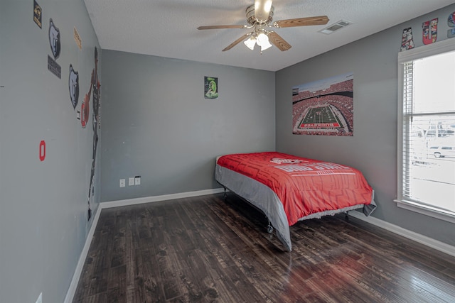 bedroom with dark wood-type flooring, ceiling fan, and a textured ceiling