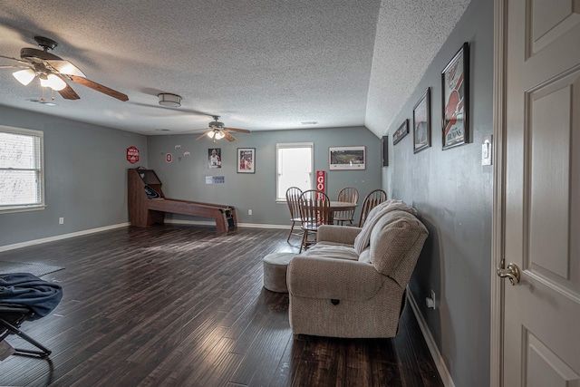 living room with dark wood-type flooring, a textured ceiling, vaulted ceiling, and a healthy amount of sunlight