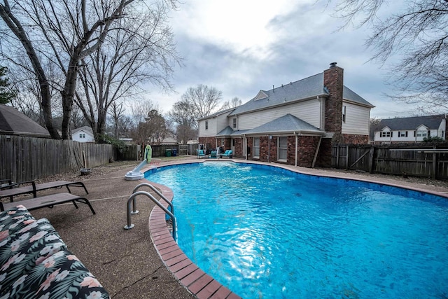 view of pool with a water slide and a patio