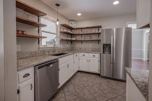 kitchen featuring pendant lighting, white cabinets, stainless steel appliances, sink, and light stone counters