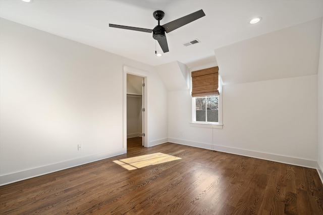 unfurnished bedroom featuring ceiling fan, dark wood-type flooring, a closet, and a walk in closet