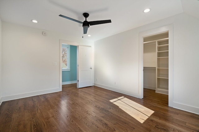 unfurnished bedroom featuring ceiling fan, a walk in closet, a closet, and dark hardwood / wood-style flooring