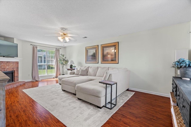 living room with ceiling fan, a fireplace, a textured ceiling, and hardwood / wood-style flooring