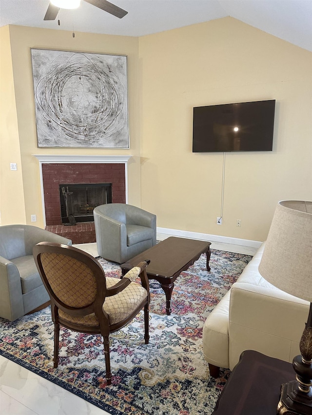 living room with ceiling fan, vaulted ceiling, and a fireplace