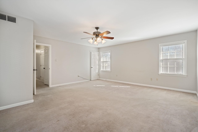 empty room featuring ceiling fan, plenty of natural light, and light colored carpet