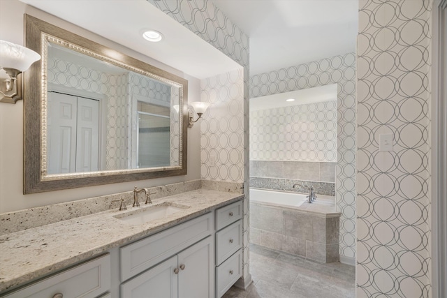 bathroom featuring tiled bath, vanity, and tile patterned flooring