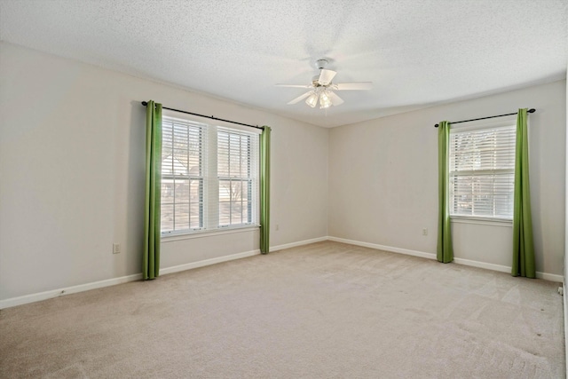 carpeted empty room with ceiling fan, a textured ceiling, and a healthy amount of sunlight