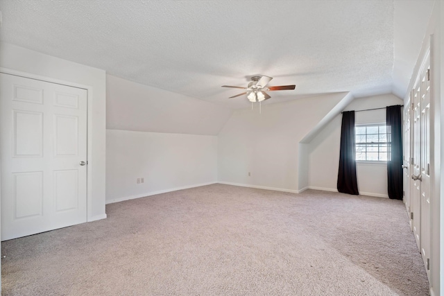 additional living space with ceiling fan, a textured ceiling, light carpet, and vaulted ceiling