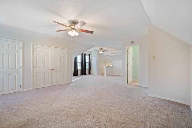 additional living space with light carpet, vaulted ceiling, a textured ceiling, and ceiling fan