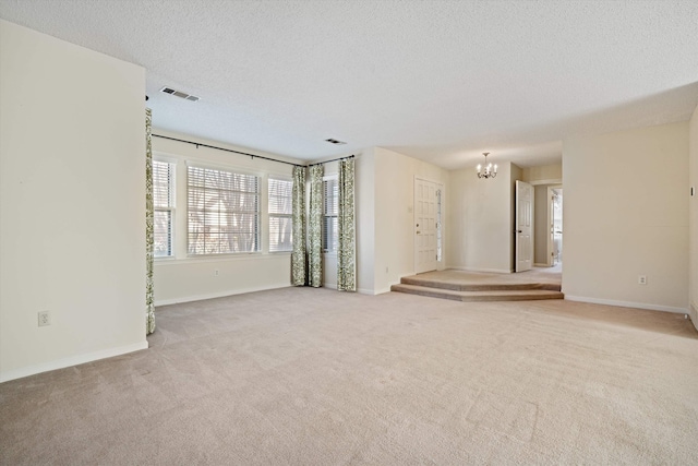 carpeted spare room featuring a textured ceiling and an inviting chandelier