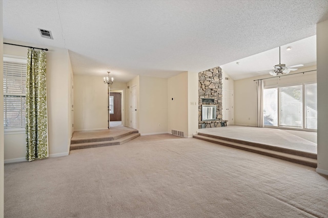 unfurnished living room featuring lofted ceiling, a stone fireplace, ceiling fan with notable chandelier, and a textured ceiling