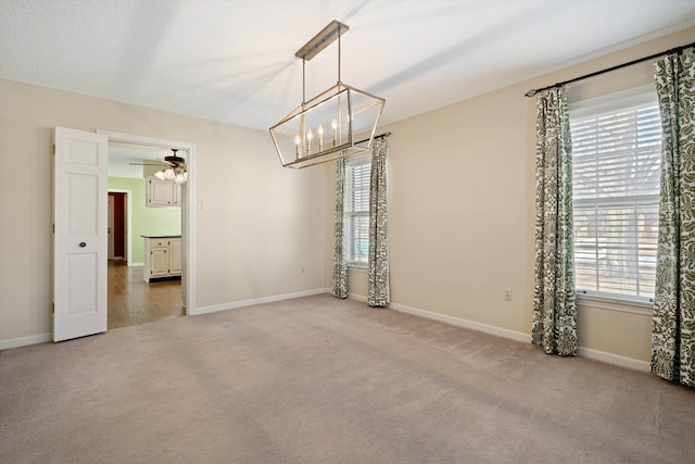 unfurnished room featuring ceiling fan with notable chandelier, plenty of natural light, and carpet