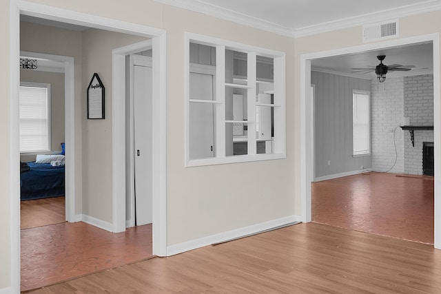 unfurnished living room with hardwood / wood-style flooring, crown molding, ceiling fan, and a fireplace