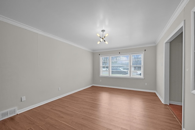 spare room featuring light wood-type flooring, a notable chandelier, and crown molding