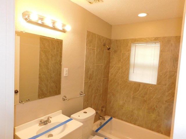 full bathroom with toilet, a textured ceiling, tiled shower / bath combo, and vanity