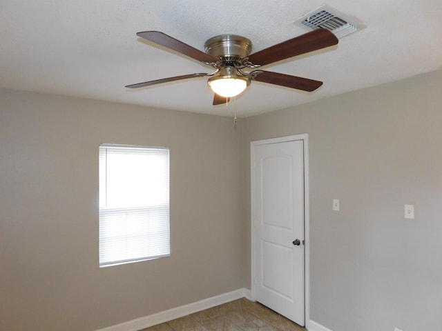 tiled spare room with ceiling fan