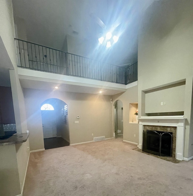 unfurnished living room featuring carpet floors and a towering ceiling