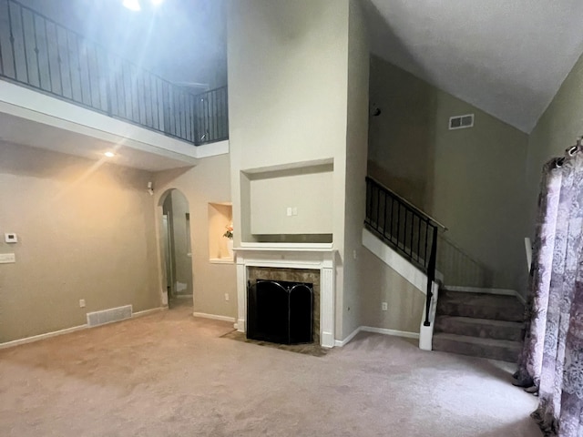 unfurnished living room featuring light colored carpet and high vaulted ceiling