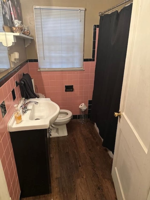 bathroom with toilet, tile walls, wood-type flooring, and vanity