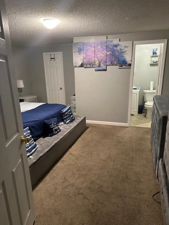 carpeted bedroom featuring ensuite bath and a textured ceiling