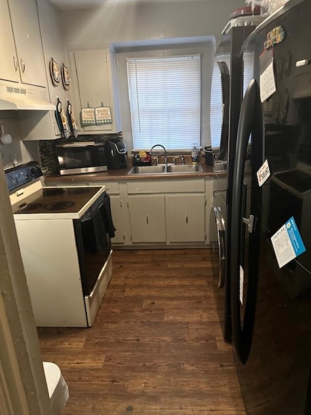 kitchen featuring black refrigerator, electric range, sink, and white cabinetry